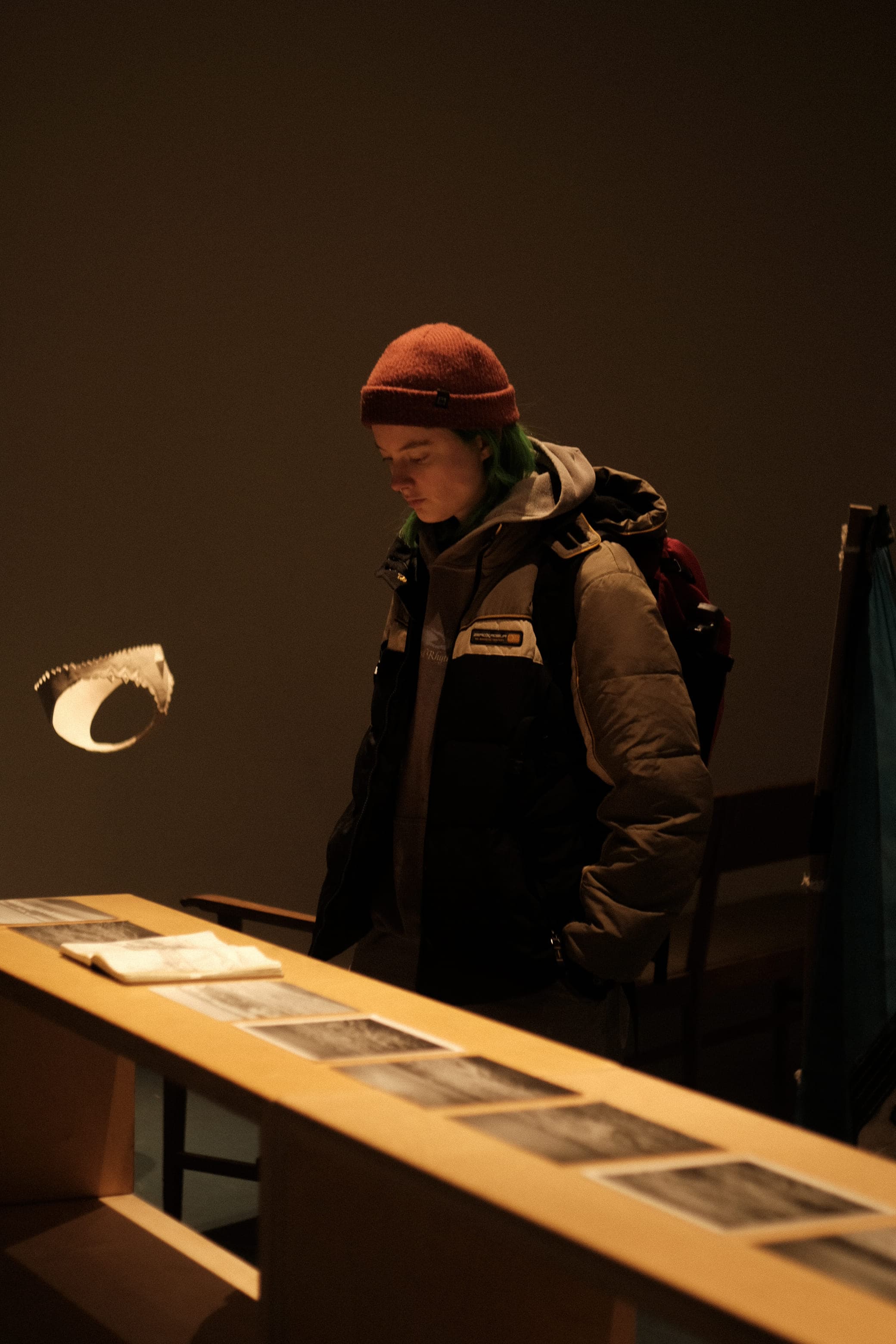 somebody looking at images splayed out on a table in front of them, with the ceramic underwear hanging in the back