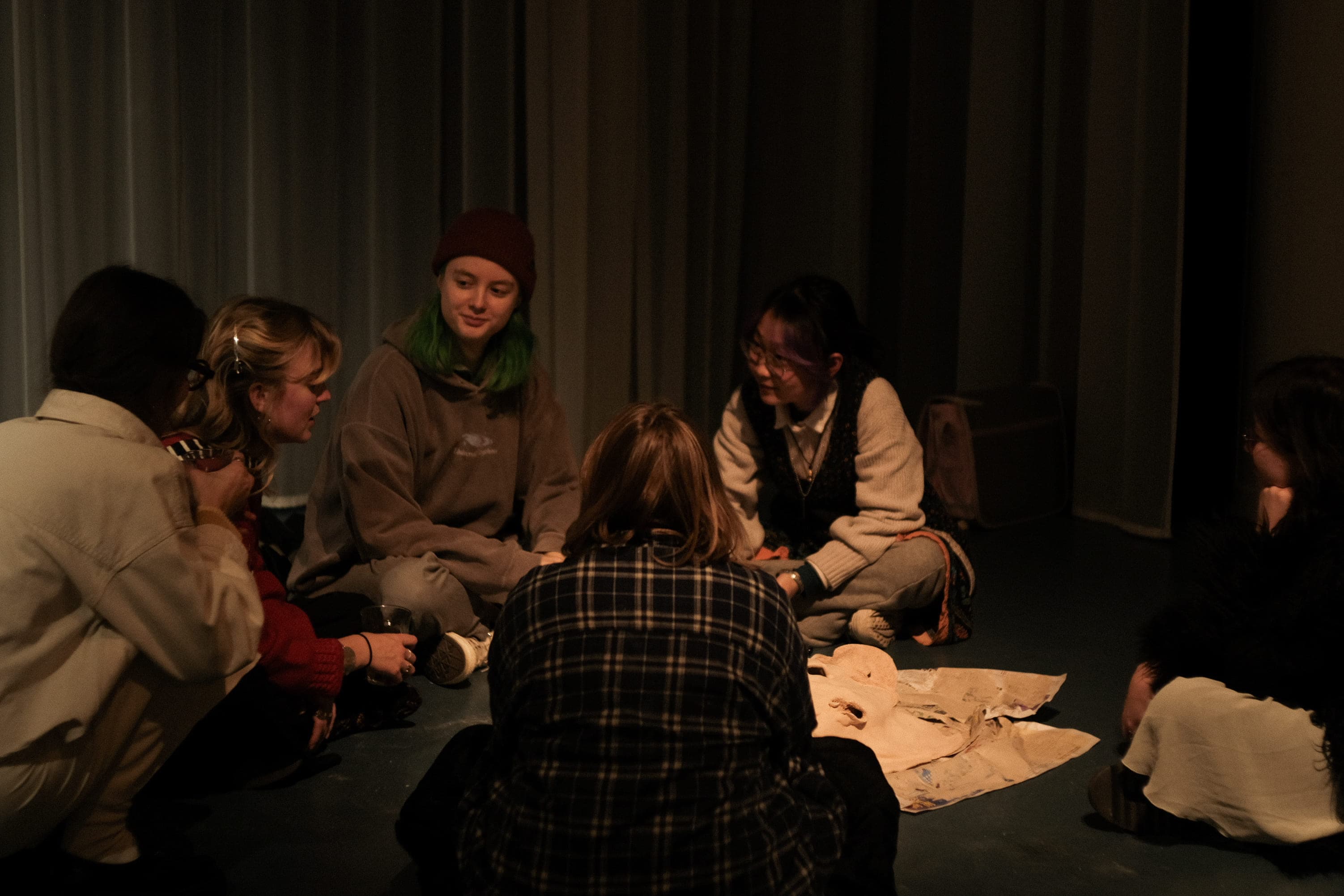 people sitting on the ground in dim lighting