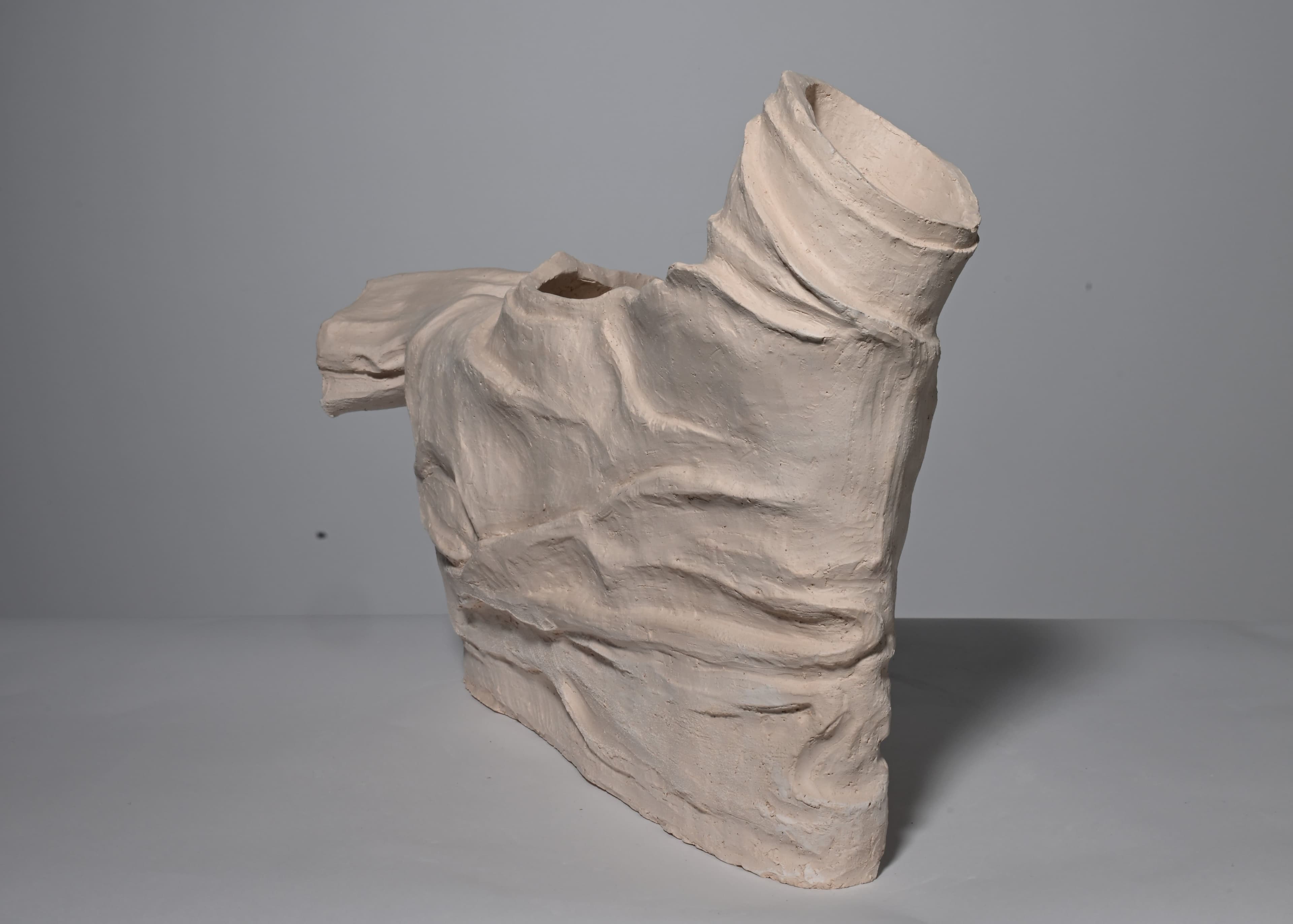 clay sculpture in the shape of wrinkled shirt, bisque fired side view